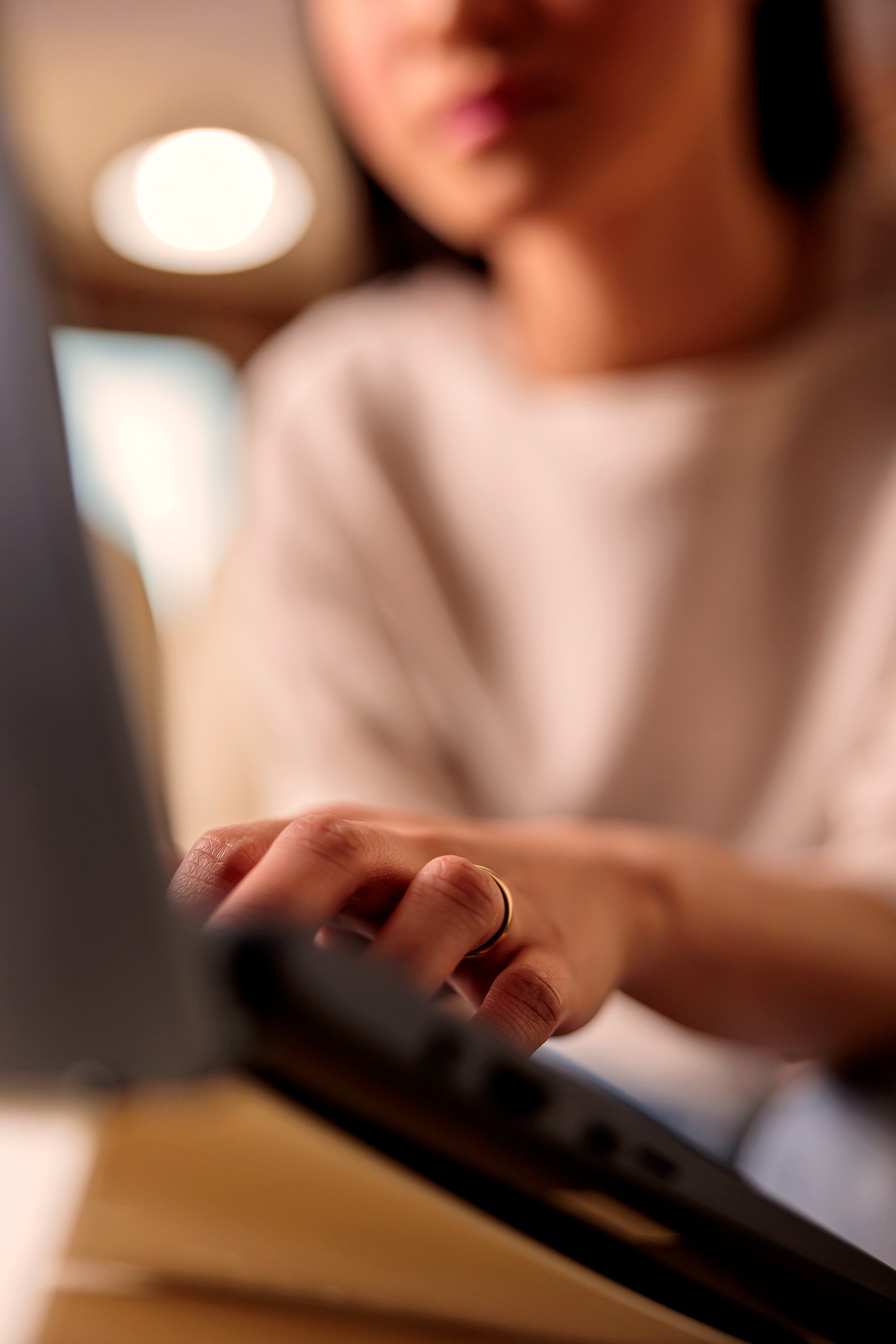 Nahaufnahme einer Hand, die auf einer Laptop-Tastatur tippt, unscharfe Person im Hintergrund